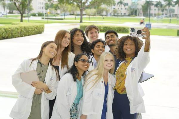 FAU Medical Students taking group selfie in front of Schmidt College of Medicine building